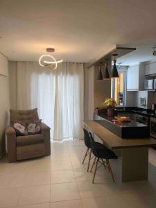 eine Küche und ein Wohnzimmer mit einem Tisch und einer Couch in der Unterkunft Condomínio pé na areia com lazer completo - PCD in Barra Velha