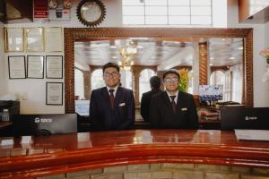two men in suits standing in front of a mirror at Quechua Hotel Cusco in Cusco