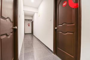 a hallway with two brown doors and a hallwayngth at Hotel O IRA Sathyajyothi Comfort in Bengaluru