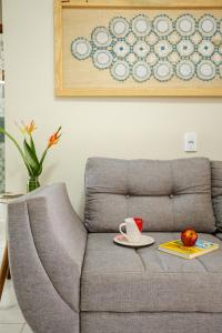 ein graues Sofa mit einer Tasse Kaffee und einem Apfel in der Unterkunft Casa no PREÁ COM PISCINA ! in Prea