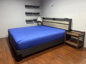 a bed with a blue bedsheet and a chair in a room at SMILE HOME GUESTHOUSE in Rayong