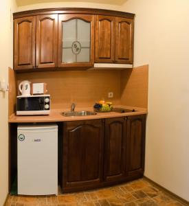 a kitchen with wooden cabinets and a sink and a microwave at Apartments & Studios Mountain Romance in Bansko