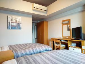 a hotel room with a bed and a desk with a television at Hotel Route-Inn Sanofujioka Inter in Sano