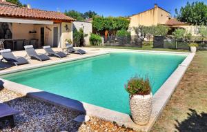 a swimming pool in a yard with chairs and a house at La Villa Du Colombier in Barbentane