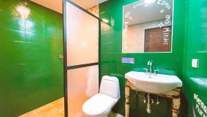 Baño verde con lavabo y espejo en Malaika Hostel Medellín, en Medellín