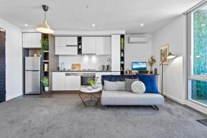 een woonkamer met een bank en een keuken bij Chic 1-Bed with Balcony Views and Amenities in Melbourne
