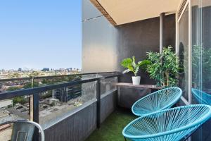 een balkon met blauwe stoelen en uitzicht op de stad bij Chic 1-Bed with Balcony Views and Amenities in Melbourne