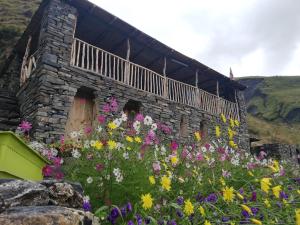 a stone building with flowers in front of it at Fortress House Khakhabo in Khakhabo