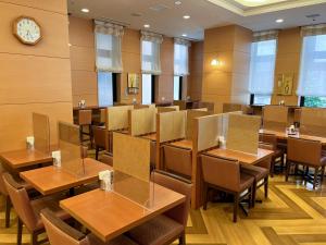 a restaurant with tables and chairs and a clock at Hotel Route-Inn Sapporo Ekimae Kitaguchi in Sapporo