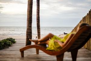 una mujer sentada en una silla en la playa en Casa ADOBE Preá - FRENTE MAR!, en Prea