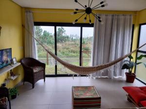 una hamaca en la sala de estar con una gran ventana en Casa de Praia a 550m da praia de Balneário Rosa do Mar e 350m da Lagoa da Tapera. en Passo de Torres