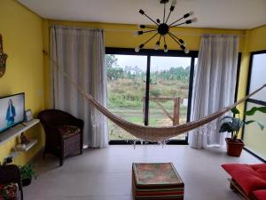 een hangmat in een woonkamer met een groot raam bij Casa a 550m da praia e 350m da Lagoa da Tapera. in Passo de Torres