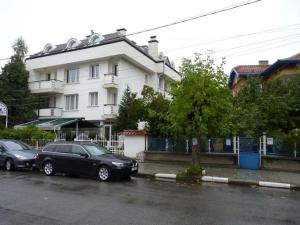 dos autos estacionados en un estacionamiento frente a un edificio en Niko Hotel, en Samokov