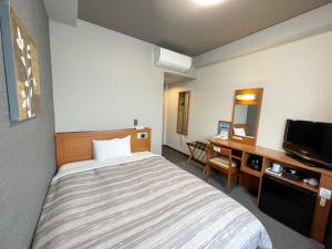藤枝市にあるホテルルートイン藤枝駅北のベッドとデスクが備わるホテルルームです。