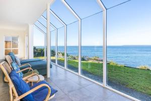 een woonkamer met grote ramen en uitzicht op de oceaan bij Neptune I Absolute Beachfront I Stunning Views in Culburra Beach