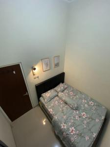 ein kleines Schlafzimmer mit einem Bett mit Blumendecke in der Unterkunft Noosa Villa - Kota Batu in Batu