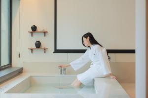 Eine Frau, die auf einem Waschbecken im Badezimmer sitzt. in der Unterkunft Aank Hotel Incheon Wolgot in Siheung