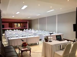 a conference room with white tables and chairs and a laptop at Siam Boutique Hotel โรงแรมสยามบูทีค in Buriram