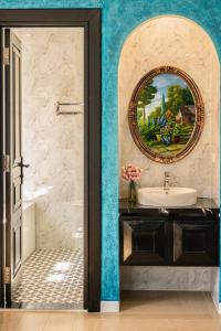 a bathroom with a sink and a painting on the wall at Hoàng Hôn Tím Boutique Hotel in Phú Quốc