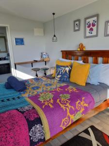 ein Schlafzimmer mit einem Bett mit einer bunten Decke darauf in der Unterkunft Denchys B&B in Matamata