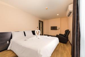 a bedroom with a large white bed and a chair at Zensation The Residence Bangkok in Bangkok