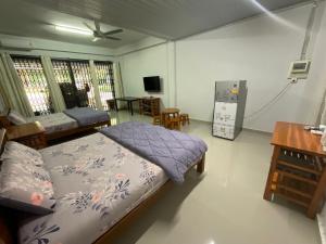 - une chambre avec un lit, une table et un réfrigérateur dans l'établissement MEGIE HOMESTAY PREMIER BETONG Thailand, à Betong