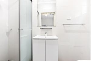 a white bathroom with a sink and a shower at Newtown Backpackers in Sydney