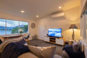a living room with a couch and a flat screen tv at Amazing Lake Views in Queenstown