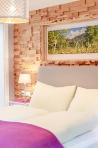 a bedroom with a white bed with a wooden wall at Zeiserhof in Ramsau am Dachstein