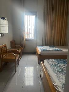 Habitación con 3 camas, silla y ventana en Bắc Nam Hotel DN by - BAY LUXURY, en Da Nang