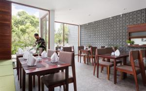 a dining room with tables and chairs and a man in the background at The Calm Oasis in Phumĭ Réach Born