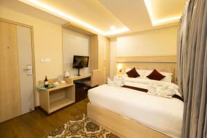 - une chambre avec un grand lit blanc et une télévision dans l'établissement Divine Kathmandu Hotel, à Katmandou