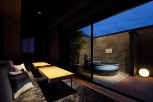 baño con bañera y una mesa en la terraza en Yatomi Hotel Nuqu Natural Hot Spring, 
