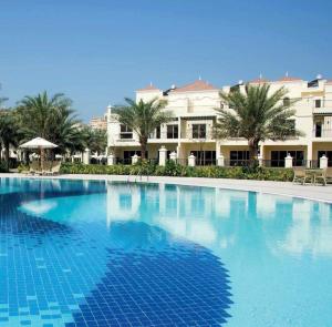 a large swimming pool in front of a hotel at Spacious, Cozy Villa with Pool Access in Ras al Khaimah