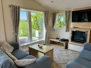 a living room with a couch and a fireplace at Fable Lodge Tattershall Lakes - luxury lakeside lodge with hot tub in Tattershall