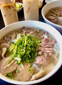 a bowl of soup with meat and greens on a table at Hoàng Hôn Tím Boutique Hotel in Phú Quốc