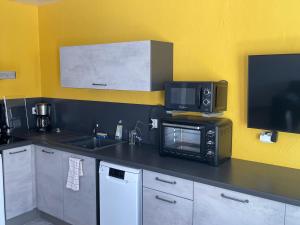 a kitchen with a microwave and a television on a counter at T2 cosy Le Pouldu, plages à 300m in Clohars-Carnoët +8 photos