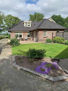 una casa in mattoni con fiori viola in un cortile di Vakantiehuis de Haar Ambt-Delden ad Ambt Delden