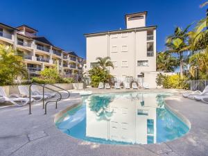 einen Pool mit Stühlen und ein Gebäude in der Unterkunft Bella Mare Coolangatta Beachside Apartments in Gold Coast