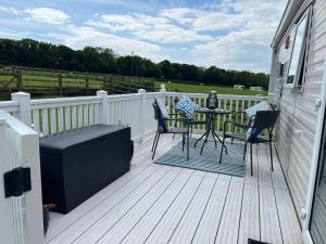 a deck with two chairs and a table on it at Countryside 3-bedroom Static Caravan in Llanerchymedd