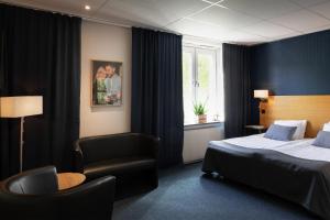 um quarto de hotel com uma cama e uma cadeira em The Brewery Hotel em Karlskrona