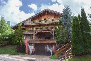 Cette maison en bois possède un balcon orné de plantes. dans l'établissement Magic Megève Bois, à Demi-Quartier