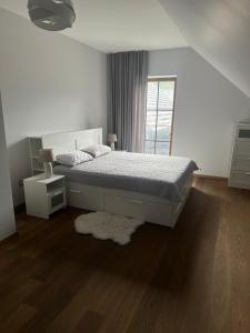 a white bedroom with a bed and a window at Papes oaze in Pape
