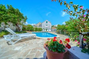 a patio with a pool and a chair and flowers at Villa Bonaca Cozy Family & Friends Retreat with Heated Pool in Sumartin