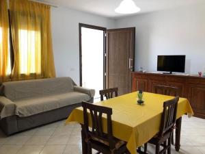sala de estar con mesa amarilla y sofá en Casa Vacanze Orchidea, en Cabras