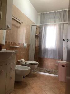 Un baño con inodoro, lavabo y ducha. en Casa Vacanze Orchidea, en Cabras