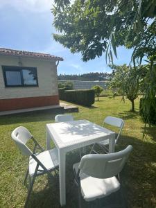 a white table and chairs in a yard at Grupo Gontad Casa Ponteceso Outrabanda 2 in Ponteceso