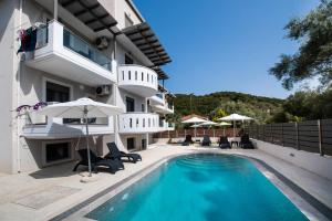a villa with a swimming pool with chairs and umbrellas at Aurelia in Nikiana