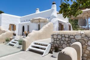 a house with white walls and stairs and an umbrella at Kallos Villas & Suites in Naxos Chora