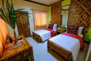 Habitación de hotel con 2 camas y mesa en Malapascua Exotic Island Dive Resort en Daanbantayan